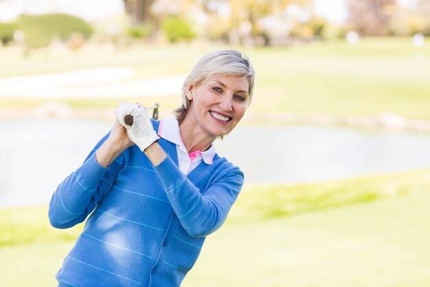 Giocatore di golf femminile che sta tenente il suo sorridere del club