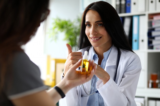 Female GP giving patient dropper jar of cannabis concentrate oil