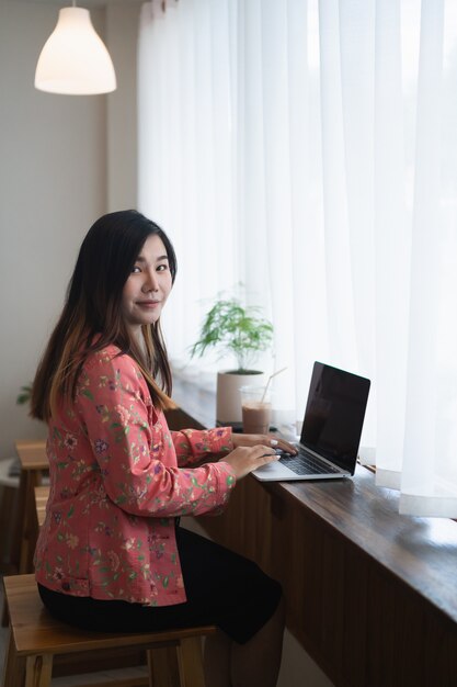 Female graphic designer artist using laptop working in windowsill at the cafe