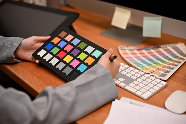 Female graphic designer holding a colour checker board and working at her desk