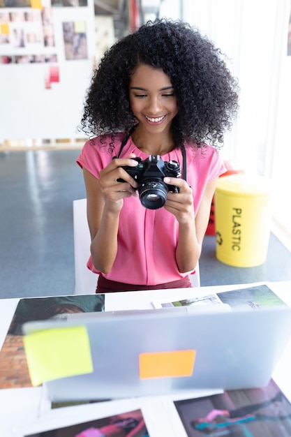 Графический дизайнер-женщина рассматривает фотографии на цифровой камере за столом