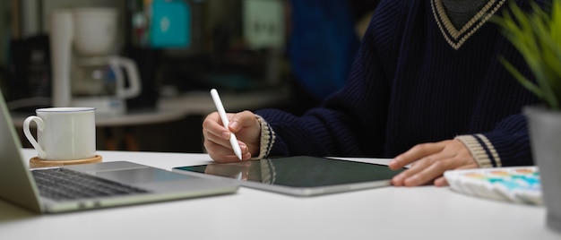 Female graphic designer working with digital tablet and laptop on white office desk