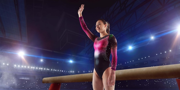 Female gymnast doing a complicated trick on gymnastics balance beam in a professional arena