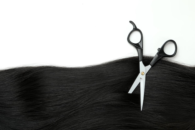 Female hair and scissors on white background