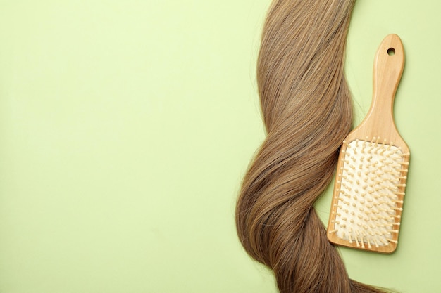 Female hair with hairbrush on green background