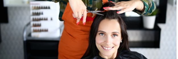 Female hairdresser cuts woman client portrait. Professional hair care