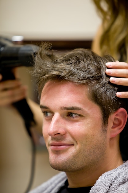 Foto parrucchiere femminile che asciuga i capelli del suo cliente maschio
