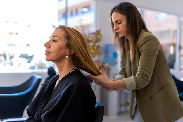 Female hairdresser examining hair of client in salon