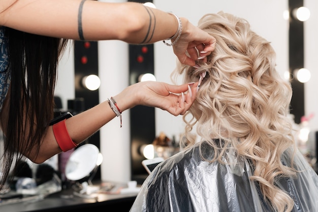 A female hairdresser makes bride hairstyle