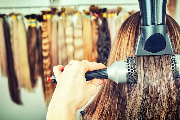 写真 ヘアブラシとヘアドライヤーを使用した女性美容師