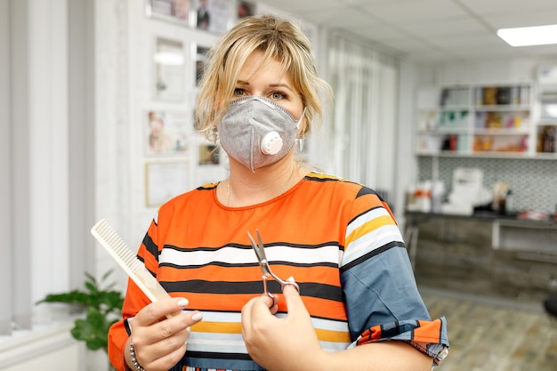 Parrucchiere femminile che indossa una maschera protettiva in salone durante l'epidemia di coronavirus