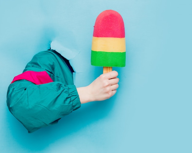 Female hand in 90s style jacket holding ice-cream 