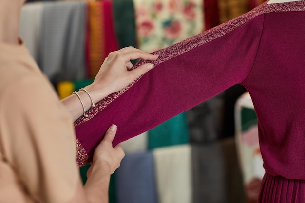 Female hand adjusts dress on the mannequin