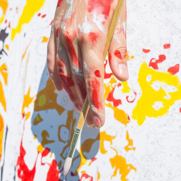 ペンキで塗られる芸術家の女性の手はブラシを握る