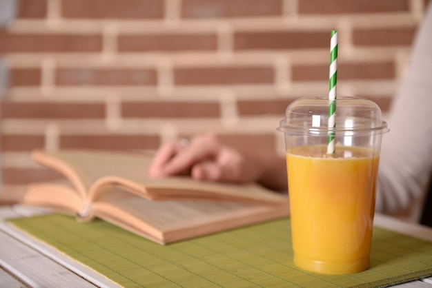 Фото Женская рука за столом с фаст-фудом закрытая чашка апельсинового сока на фоне кирпичной стены