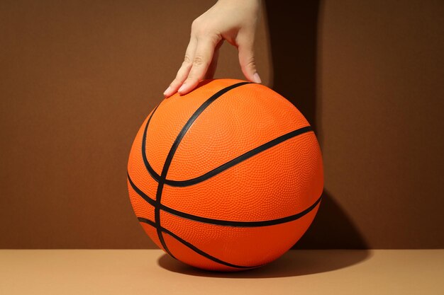 Female hand and basketball ball on two tone background