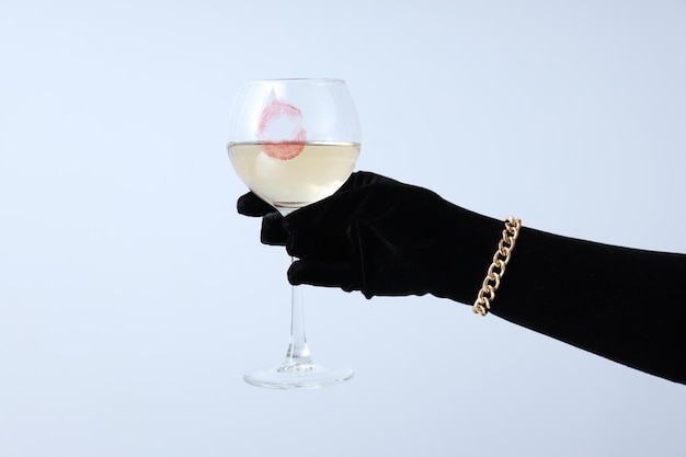 Female hand in black glove holds glass of wine with kiss on white background