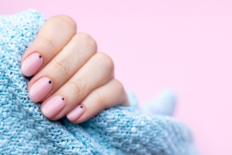 Female hand in a blue knitted sweater with beautiful manicure