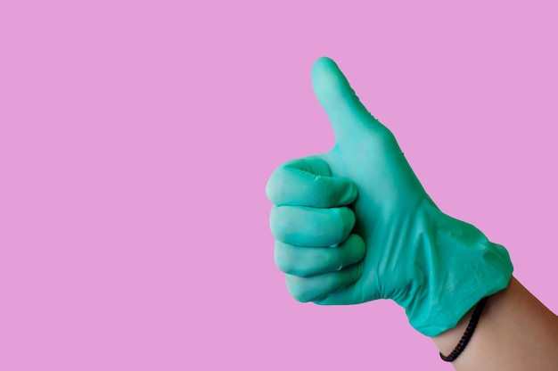 Female hand in blue latex glove makes thumbs up like gesture