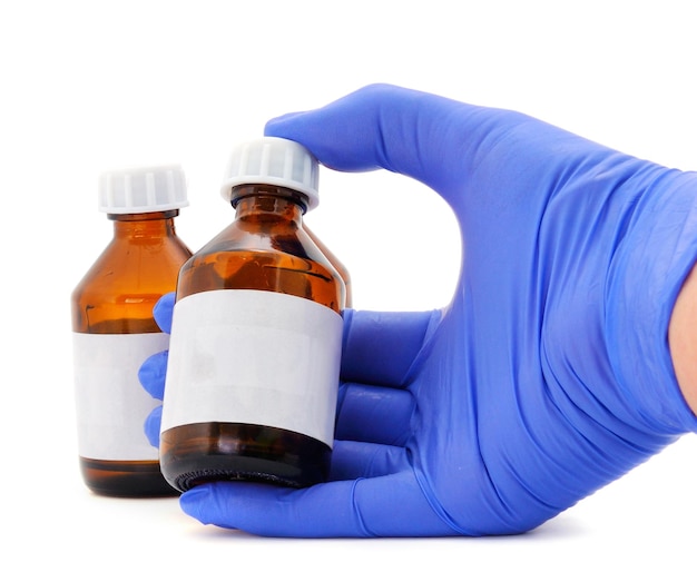 Female hand in blue latex medical glove holds a brown glass bottle for medicines