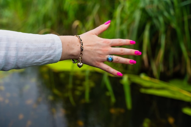 Female hand in bracelet and ring with blue stone with pink manicure closeup