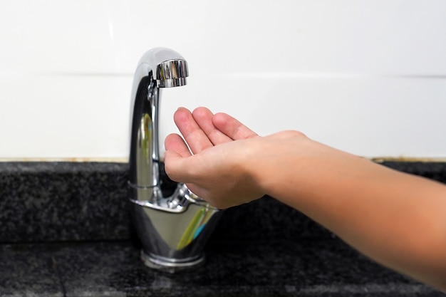 Female hand checks the water in the tap