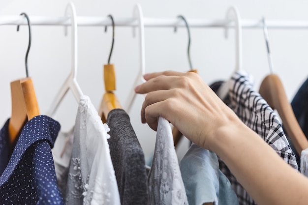 Female hand chooses clothes on a hanger