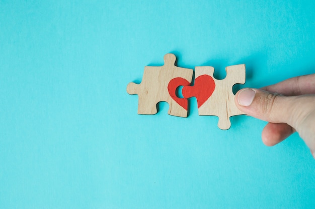 Foto puzzle di collegamento della mano femminile con cuore rosso disegnato su fondo blu. amore . san valentino riconciliazione.