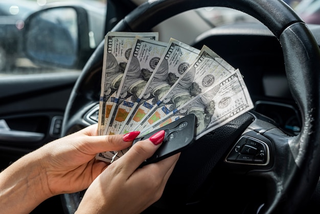 Female hand counting us dollar in a car, concept of buy or rent auto