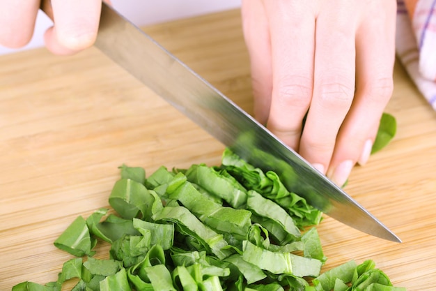 Female hand cutting greens on cutting board