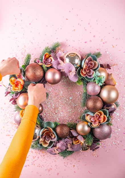 Female hand decorating beautiful unusual Christmas wreath. flat lay