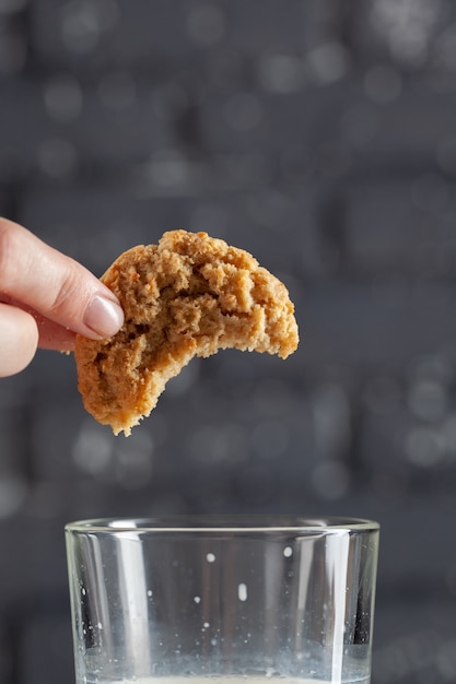 Female hand dunking cookie in milk close up