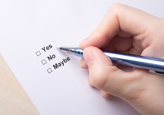 Female hand filling survey with yes, no, maybe answers with pen