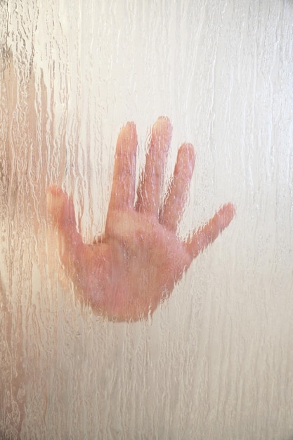 Foto mano femminile dietro lo schermo doccia in vetro smerigliato