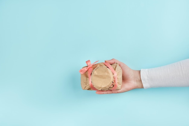 Foto la mano femminile dà una macchina fotografica avvolta in carta artigianale misterioso regalo a sorpresa