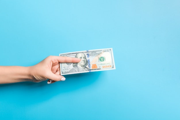 Female hand giving a bundle of dollar bills