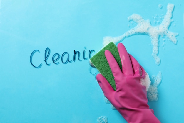 Female hand in glove wipes text Cleaning on blue background