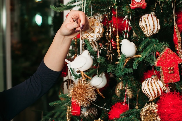 女性の手がクリスマスツリーにおもちゃを掛ける