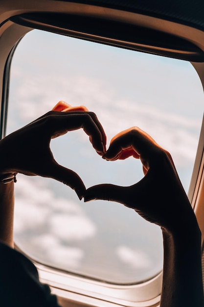 Foto mano femminile a forma di cuore vista di volo di aereo dalla finestra dell'aereo aereo aereo