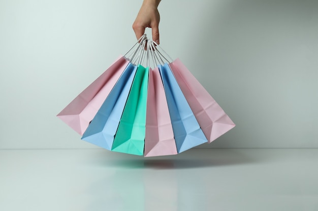 Female hand hold colorful paper bags on white