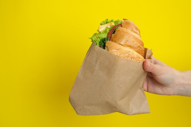 Photo female hand hold croissant sandwich on yellow