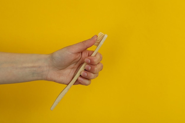 Female hand hold eco friendly toothbrushes on yellow background