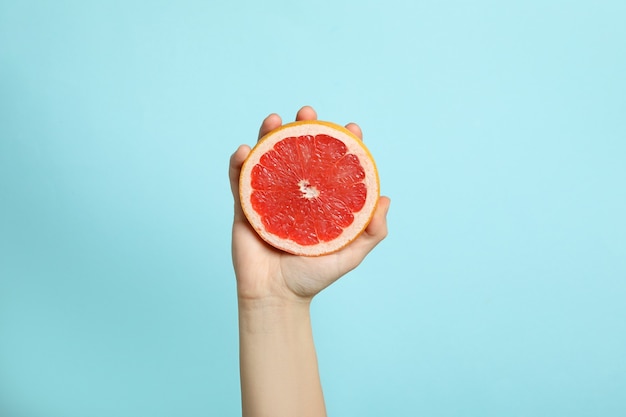 Female hand hold grapefruit on blue background