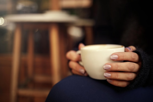 女性の手はホットコーヒーカップを保持します