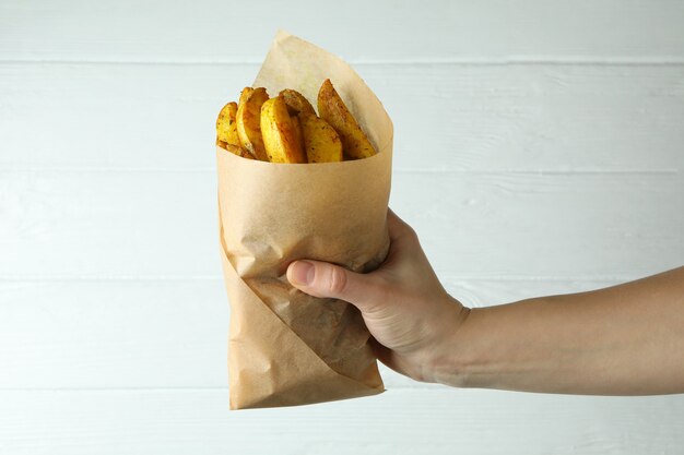 Female hand hold paper pack of potato wedges