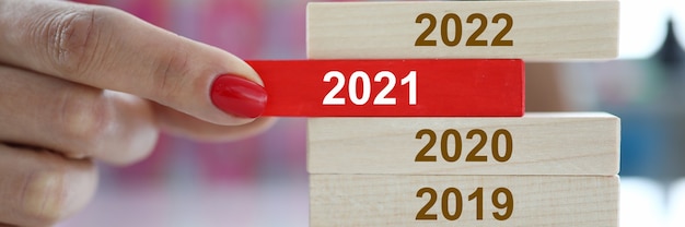 Женская рука держит красный деревянный блок с крупным планом знака 2021 года. отбивает и меняет концепцию