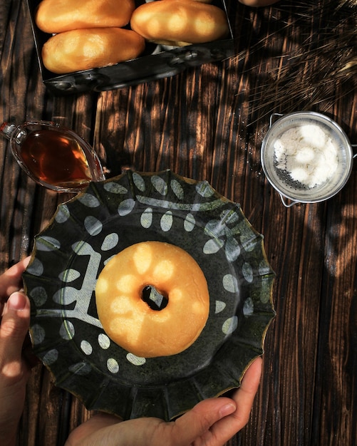 도넛 또는 도넛 도넛이 있는 여성 손 잡고 소박한 접시는 튀긴 간식입니다
