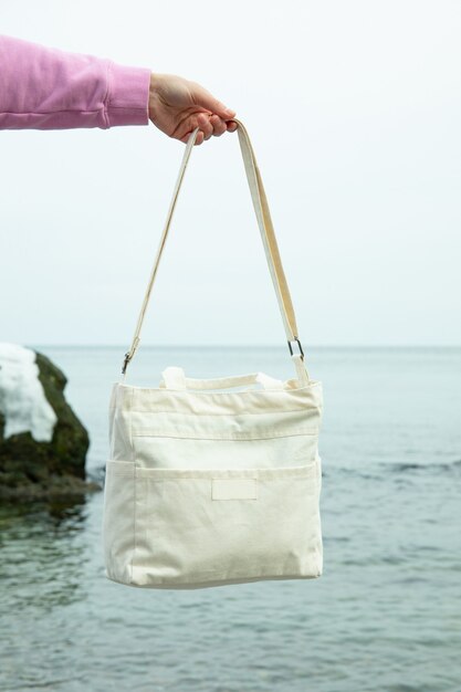 Female hand hold stylish eco bag against sea