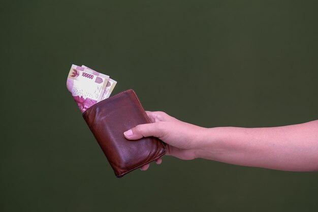Фото Женская рука держит кошелек с торчащими деньгами