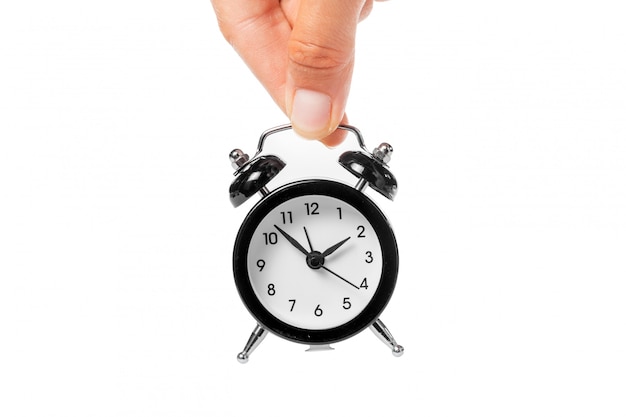 Female hand holding alarm clock on white